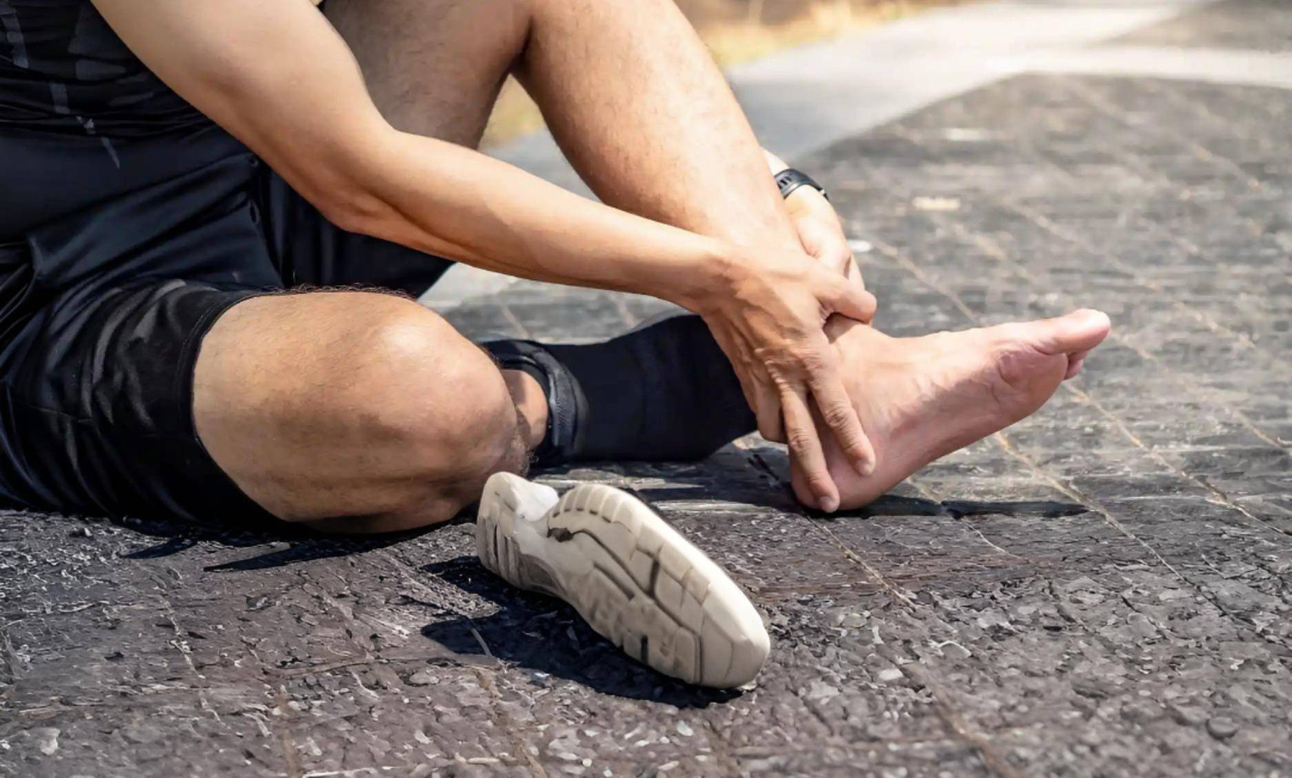 Individual experiencing ankle pain while seated outdoors; contact Foot & Ankle Center of Arizona for expert care.